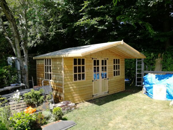 pretty wooden summer house with large porch roof in a garden