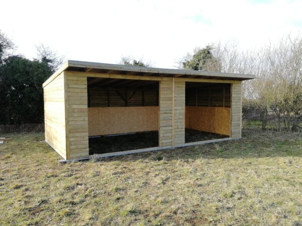 Large wooden double field shelter with two openings in a field