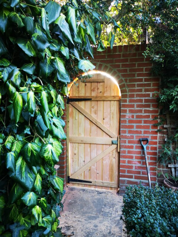beautiful wooden arched gate in a brick wall