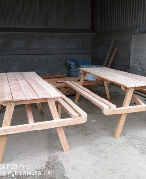 two large wooden picnic benches standing side by side in a barn
