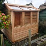 a timber potting shed shown from the sloping glass side, newly built